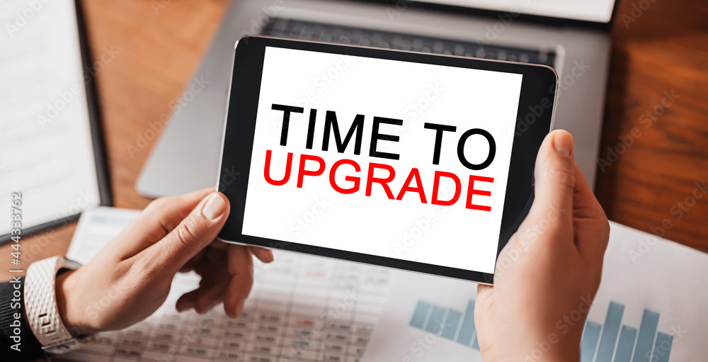 Man hands holding tablet with text Time to upgrade at workplace. Businessman working at desk with documents Man hands holding tablet with text Time to upgrade at workplace. Businessman working at desk with documents
