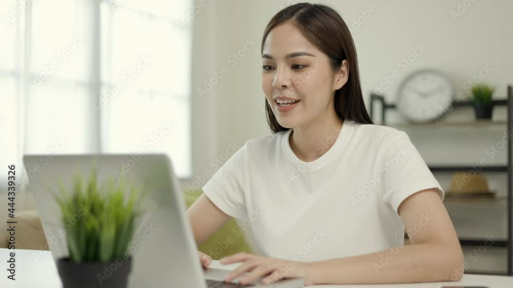 Young asian woman using laptop chatting video conference online sitting in living room at home. Business Woman looking at screen Meeting on social media live steam. Work, learning from home.