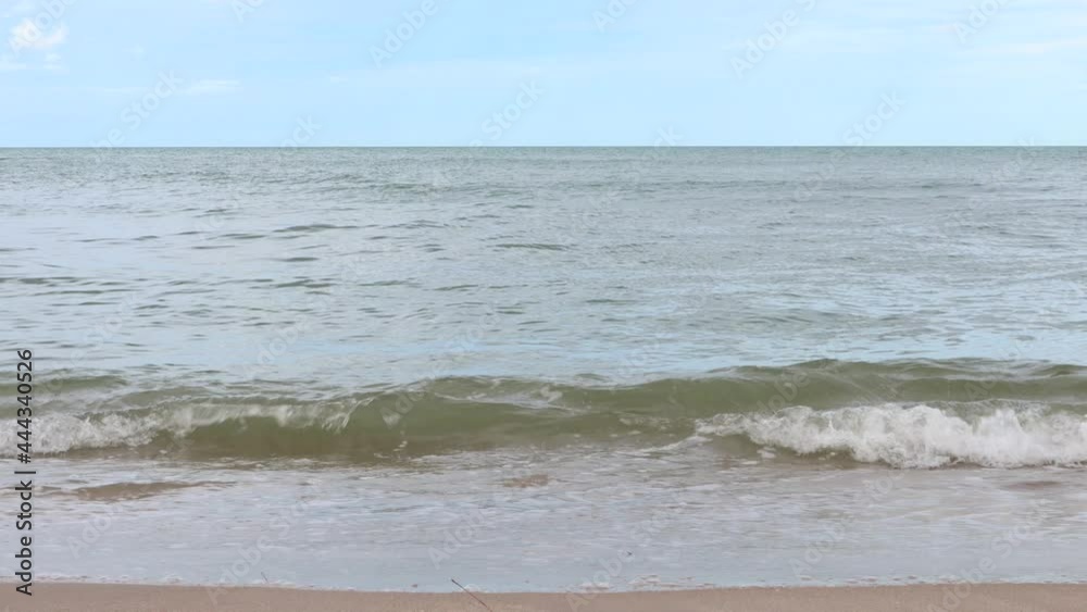 Wind blowing over sea waves on the beach in daytime. The waves hitting the empty sandy beach. Wind blowing over sea waves on the beach in daytime. The waves hitting the empty sandy beach.