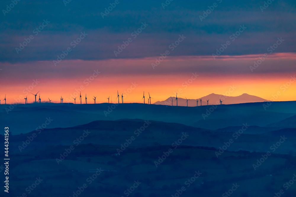 sunset in the mountains with wind turbine silhouettes
