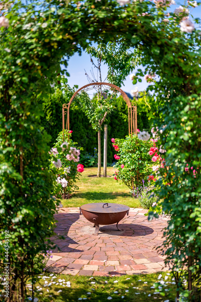 Schöner Garten mit Feuerschale und Rosenbögen als Erholungsort auf dem eigenen Grundstück