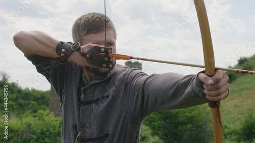 a young guy shoots a bow at a target, in nature, and hits the target, the arrow pierces the target for flight, pulls the bowstring tightly for a shot. Prores 422