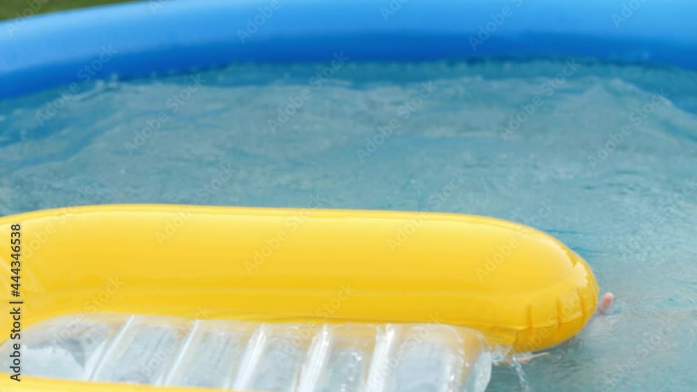 Happy baby boy in protective goggles floating on safety buoy at inflatable rubber swimming pool Happy baby boy in protective goggles floating on safety buoy at inflatable rubber swimming pool