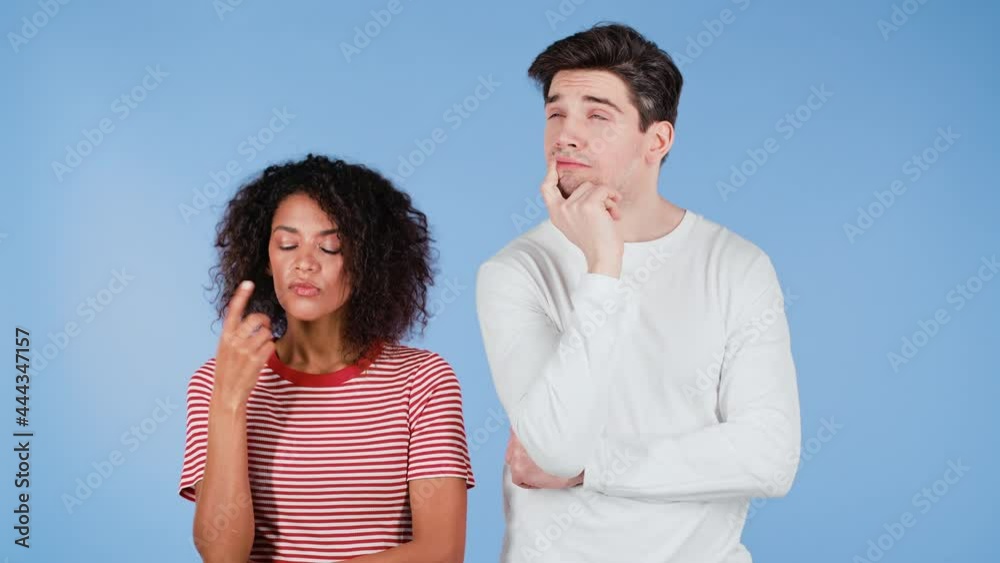 Interracial thinking pondering couple on blue studio background. Man and woman look in different directions and everyone thinks about his problem. African girl and white guy. Interracial thinking pondering couple on blue studio background. Man and woman look in different directions and everyone thinks about his problem. African girl and white guy.