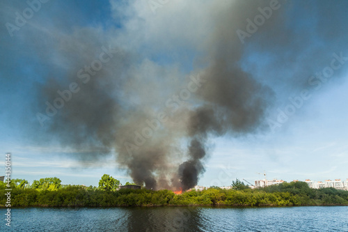 A huge column of black smoke rises from a fire near the river