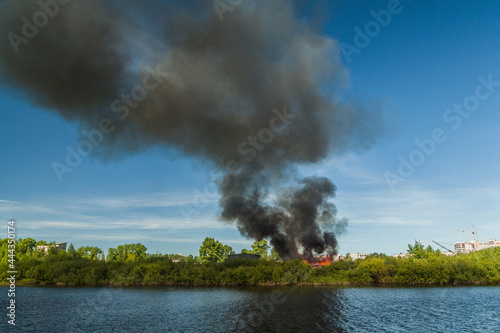 A huge column of black smoke rises from a fire near the river