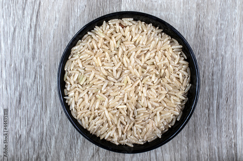 Quadro su tela Top view of integral rice on glass bowl isolated on wooden table in Brazil