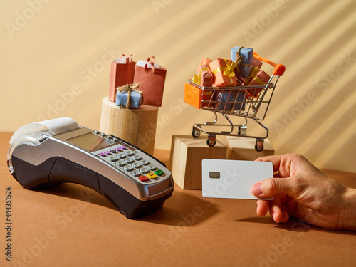 Terminal, bank card. Many purchases in beautiful boxes are in the cart. Credit purchases. Holiday discounts and sales. Focusing on the foreground.