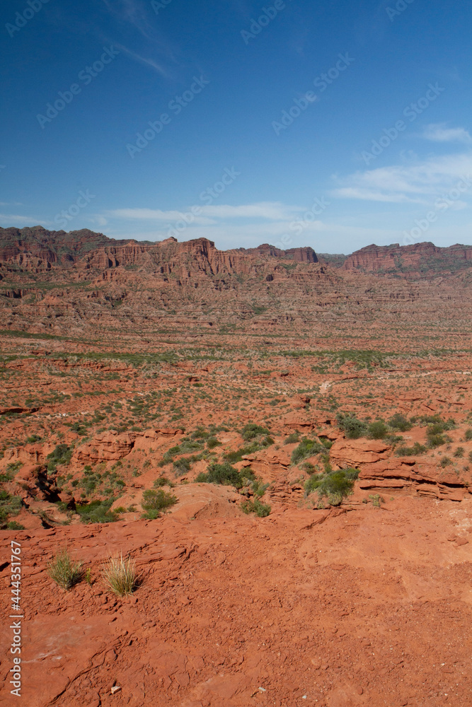 The steep canyon. Panorama view of the red desert, cliffs, orange sandstone formations and rocky mountains in the horizon in Sierra de las Quijadas national park in San Luis, Argentina. The steep canyon. Panorama view of the red desert, cliffs, orange sandstone formations and rocky mountains in the horizon in Sierra de las Quijadas national park in San Luis, Argentina.