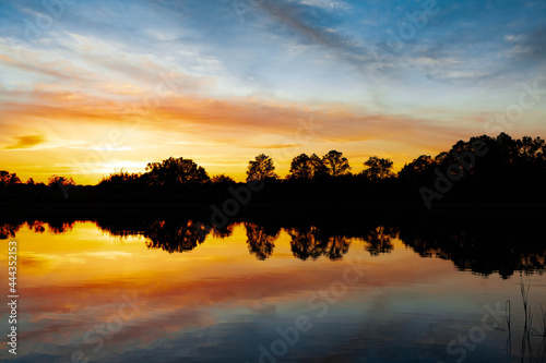 Sunset over the river  silhouette of the forest  mirror image in the water