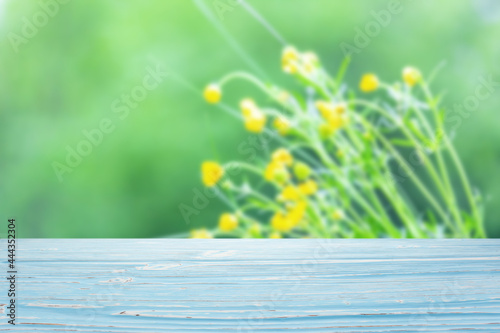 Blue wood table top on blur yellow wildflowers and foliage background