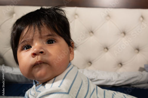 portrait of a 5 month old hispanic baby with long hair and very smiling and happy face