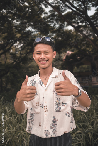 A young teenage man gives a double thumbs up giving his enthusiastic approval and support. Outdoor scene. photo