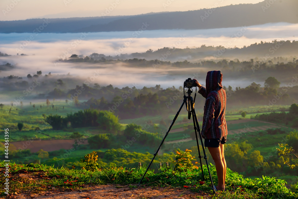Traveller takes photos of dreamy majestic landscape, sunset at horizon and watching into colorful mist and fog in morning valley.Travel Concept