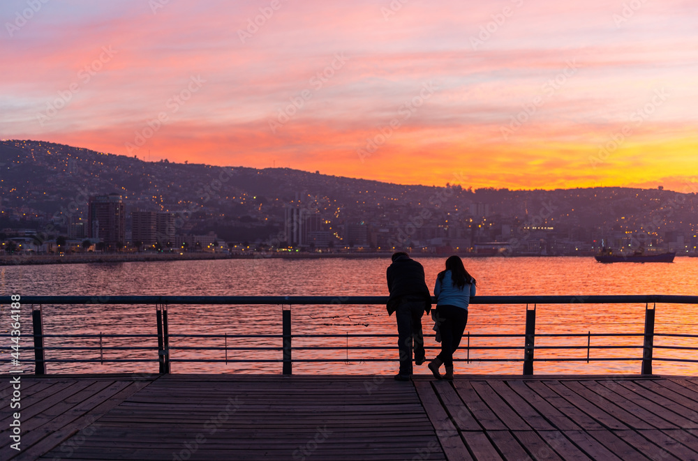 Valpraraiso skyline and bay by Pacific Ocean with a romantic couple in foreground enjoying the view at sunset, Chile.