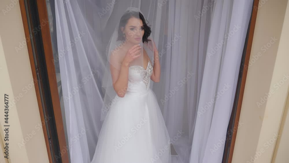 A beautiful young bride in a dress and with a long veil poses in the studio. A beautiful young bride in a dress and with a long veil poses in the studio.