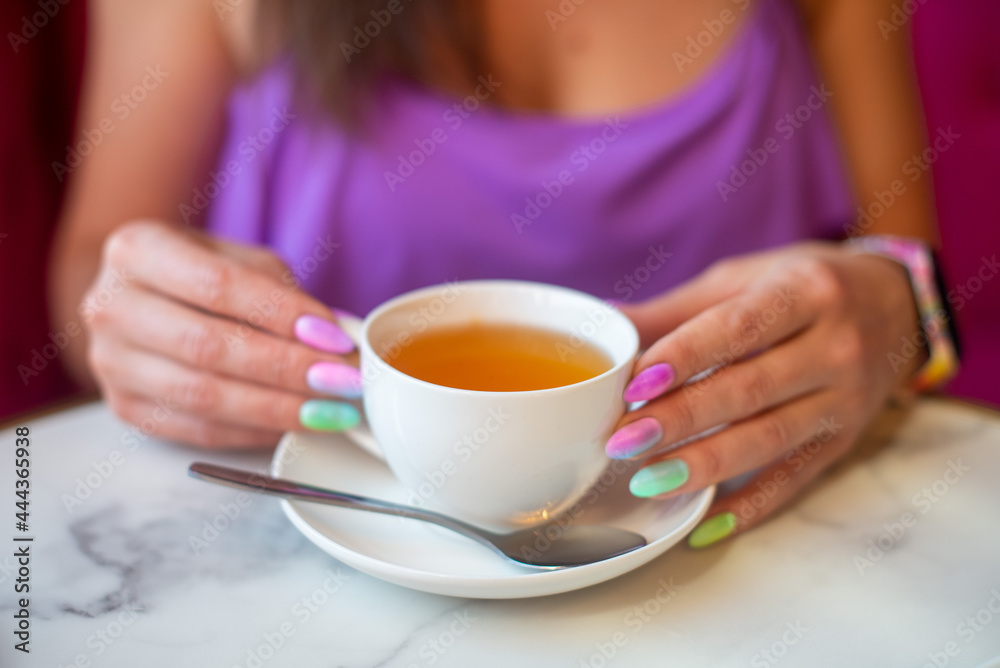 Asian woman drinking tea in a cafe with a manicure