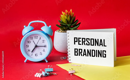 PERSONAL BRANDING text written on notepad. On a red and yellow background alarm clock, cactus and paper clips. Design project. Branding and marketing business concept. photo