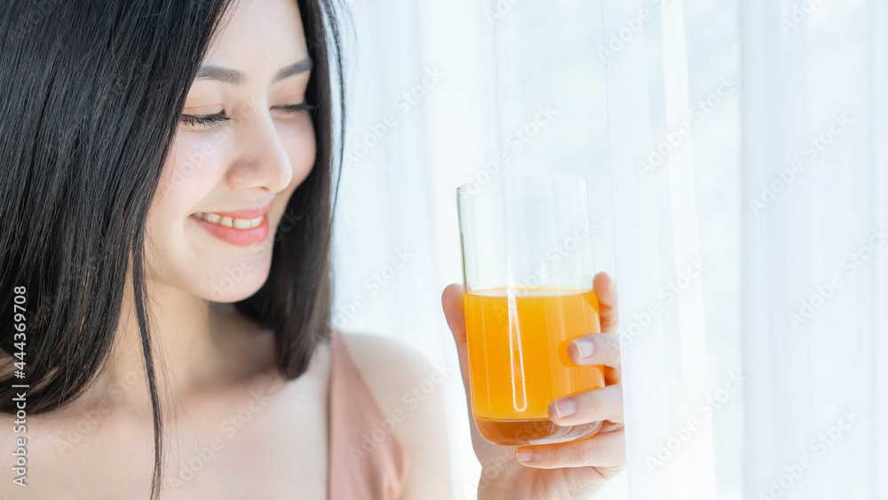 Beautiful beauty woman Asian cute girl feel happy drinking orange juice for good health in the morning , enjoying time in her home white bedroom background - lifestyle beauty woman concept Beautiful beauty woman Asian cute girl feel happy drinking orange juice for good health in the morning , enjoying time in her home white bedroom background - lifestyle beauty woman concept