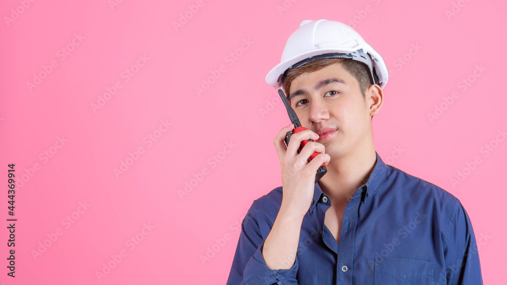 Portrait young architect man engineering wearing white helmet and hold megaphone in hand, He standing with smile on pink background Portrait young architect man engineering wearing white helmet and hold megaphone in hand, He standing with smile on pink background
