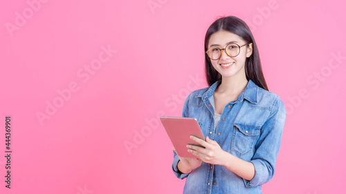 Beautiful cute girl Asian woman playing a smart phone tablet computer on pink background - lifestyle female concept
