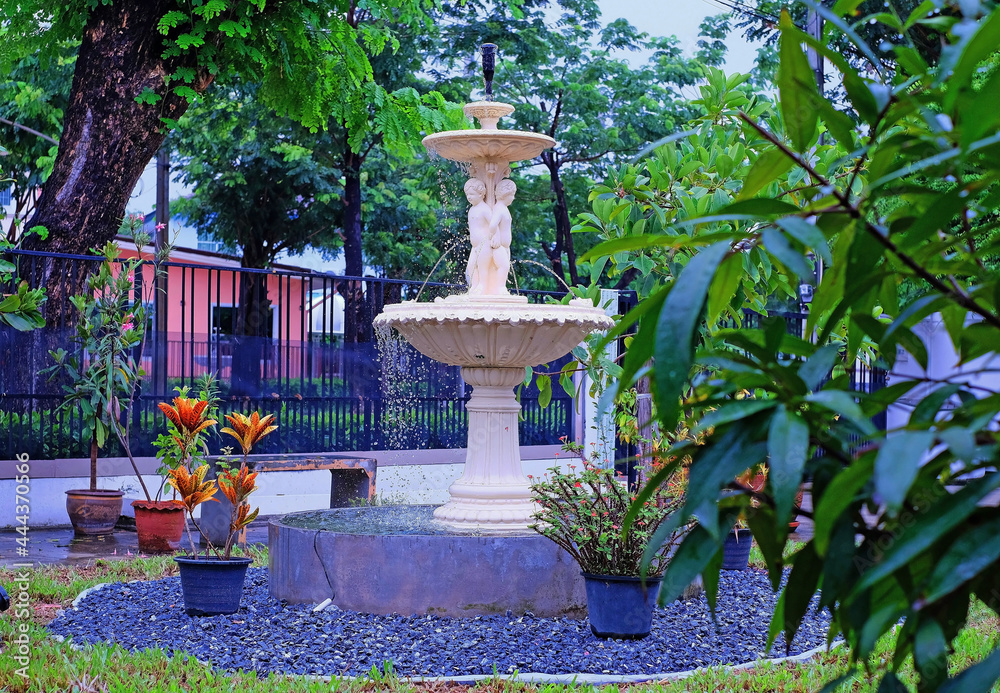 A fountain of three little boys in house garden amid trees A fountain of three little boys in house garden amid trees