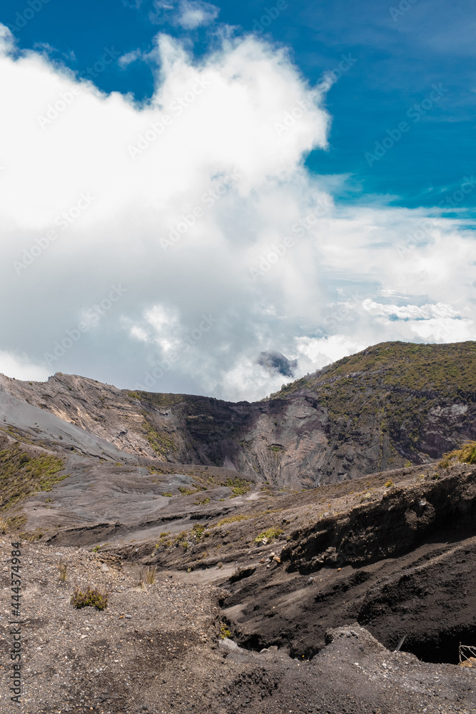 vertical shot of the main crater surrounded with little vegetation rocky and sandy terrain with blue sky in the Irazu Volcano National Park - Cartago - Costa Rica - Central America vertical shot of the main crater surrounded with little vegetation rocky and sandy terrain with blue sky in the Irazu Volcano National Park - Cartago - Costa Rica - Central America