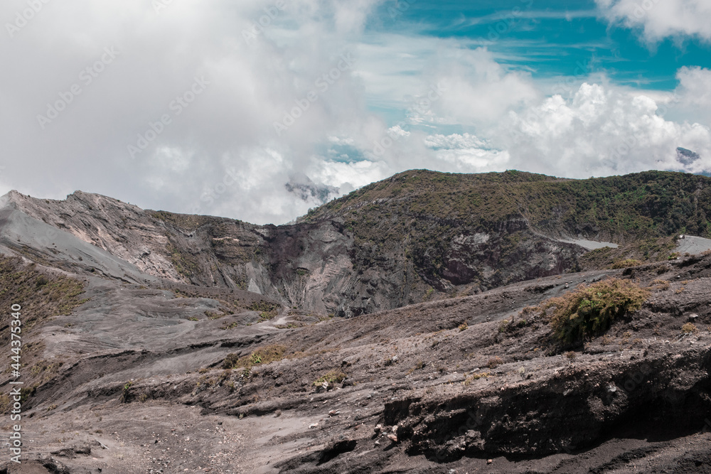 view of the main crater surrounded with little vegetation rocky and sandy terrain with blue sky in the Irazu Volcano National Park - Cartago - Costa Rica - Central America