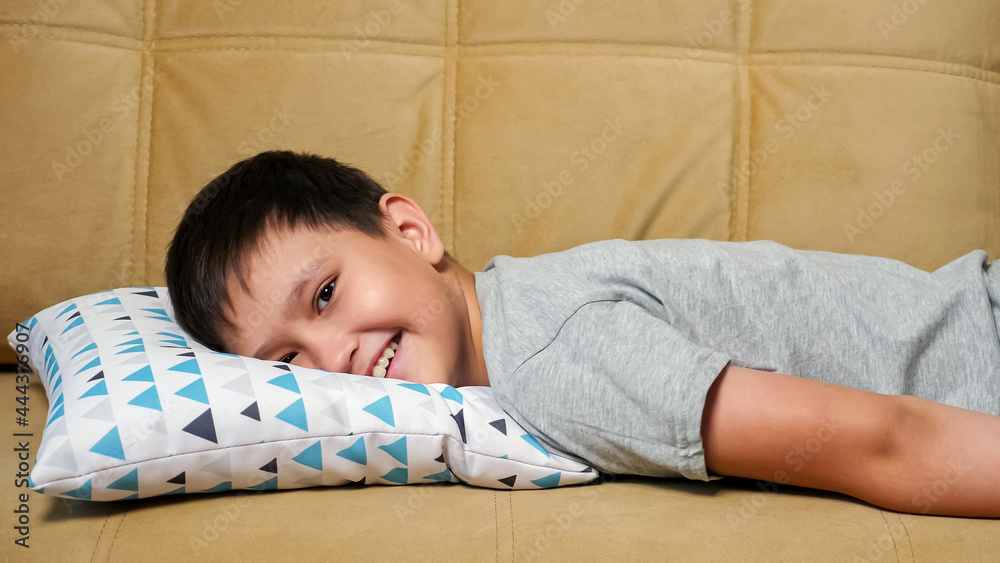 Smiling boy falls on the sofa face down, copy space