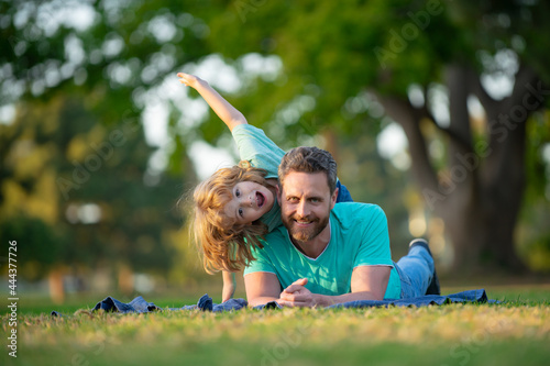 Happy father and son enjoying summer time on vacation in a sunny park. Concept of healthy holiday and family activity.