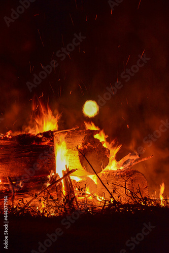 Close up of bonfire and full moon above it with hot orange embers in rural Minnesota, USA 