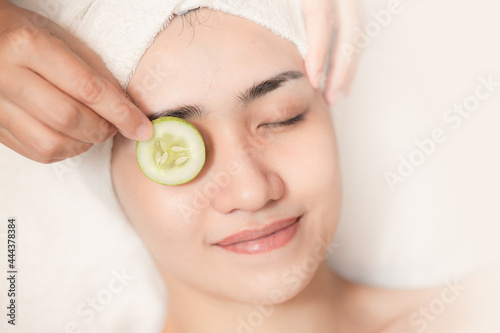 beautiful women facial skin care eyes wrinkle cucumber treatment in spa salon relax happy smile.