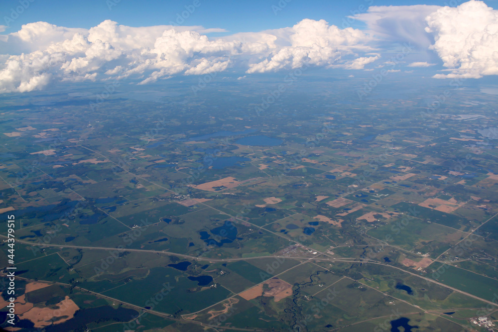 Obraz premium View of Minnesota lakes, farmland and clouds from airplane window. 