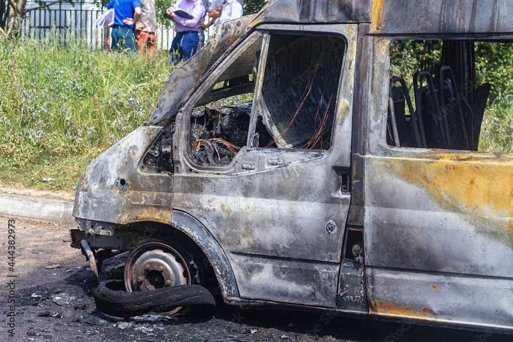 A burnt-out car on a city street, serious fire damage after a fire on the body of a passenger minibus