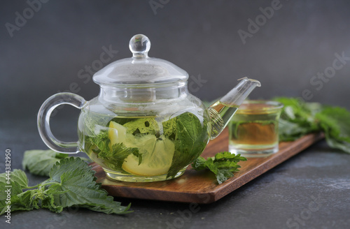 Homemade herbal tea from nettle and lemon in glass teapot.