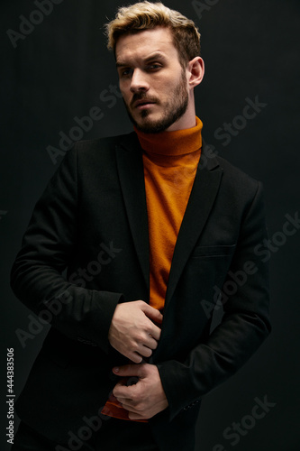 guy model in an orange sweater blonde jacket the dark background cropped view