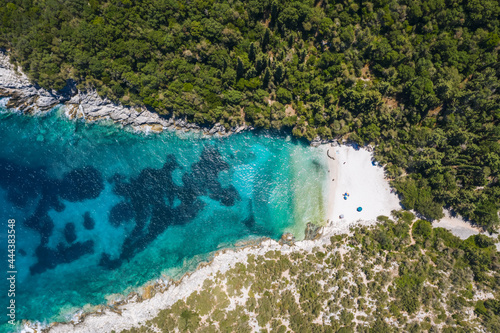 Aerial top down view of Dafnoudi beach in Kefalonia, Greece. Remote bay with pure crystal clean turquoise sea water surrounded by cypress trees
