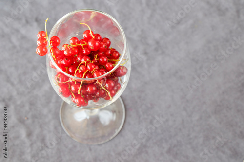 Red currant in the wineglass on the gray cloth background. Large group.
