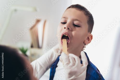 Doctor checking little boy's throat in the office