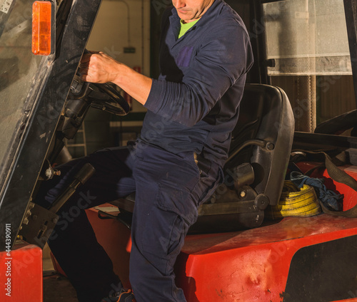 Unrecognizable young man getting off a forklift.