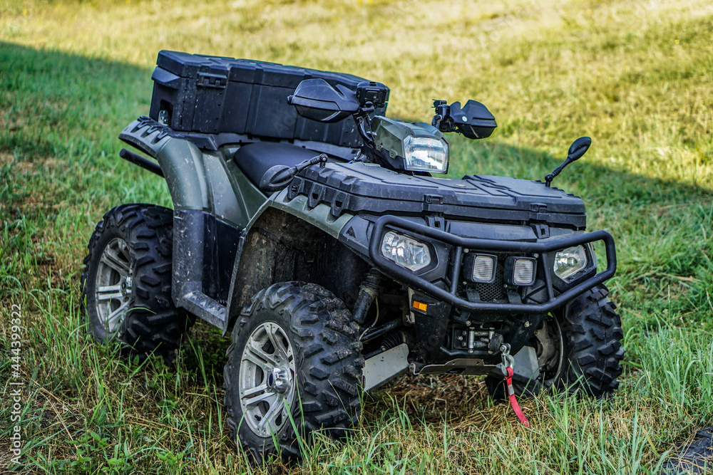 Obraz premium ATV quad bike on a background of green grass. Four-wheeled motorcycle 4x4 for sports and recreation. Off-road transport.