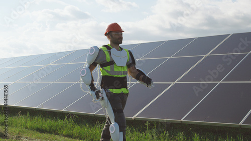Male engineer in exoskeleton walking on solar plant photo
