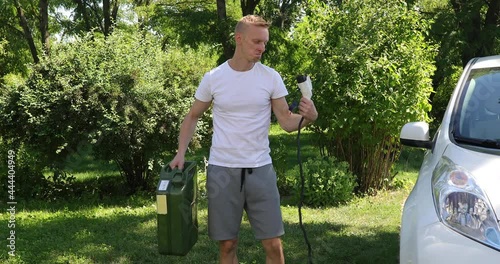 Man is standing and choosing electric charge cable with plug or gas canister selecting fuel type 