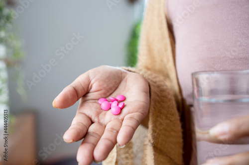 woman hand taking painkiller pink ibuprofen pills , handful of overdose medicines