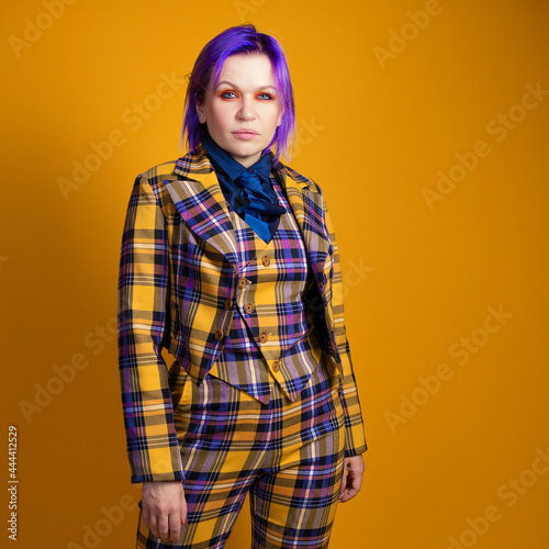 young woman with purple hair in a stylish bright plaid suit.