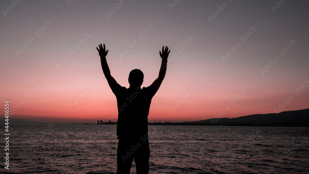 one person silhouette with hands up sea in background