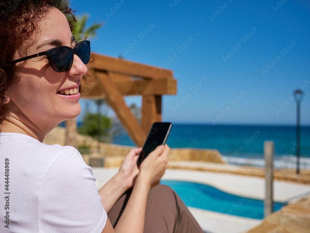 Woman leaning on a stone wall sunbathing while on vacation