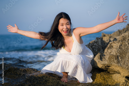 young happy and beautiful Asian woman by the sea - Attractive Chinese girl in white dress enjoying relaxed summer holidays at tropical island in travel and lifestyle concept