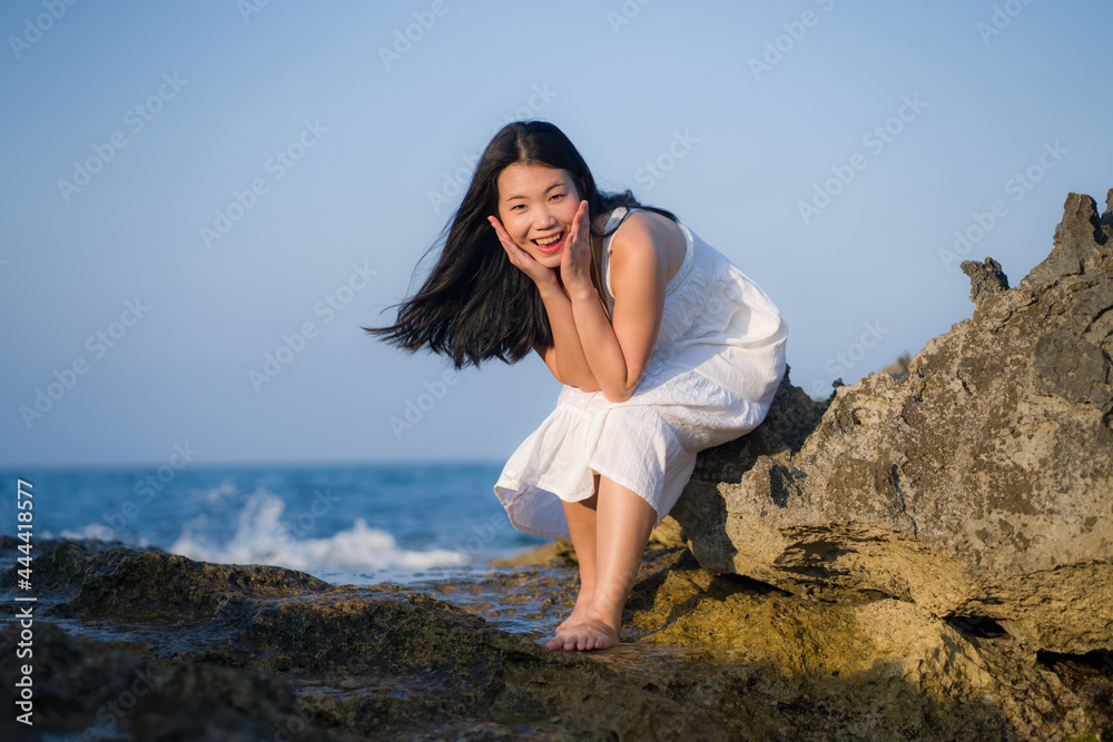 young happy and beautiful Asian woman by the sea - Attractive Korean girl in white dress enjoying relaxed summer holidays at tropical island in travel and lifestyle concept