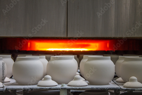 New ceramic identical white pots sent to a muffle kiln for firing at a porcelain factory in the Moscow region of Russia photo